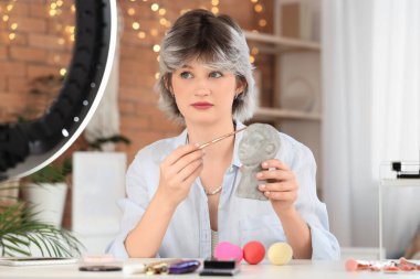 Evde makyaj fırçası ve dekoratif kafa kayıt videosu olan kadın güzellik blogcusu