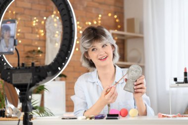 Evde makyaj fırçası ve dekoratif kafa kayıt videosu olan kadın güzellik blogcusu