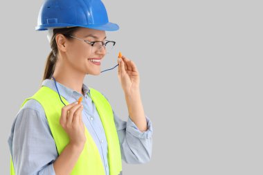 Kadın inşaatçı hafif arkaplana kulak tıkaçları yerleştiriyor