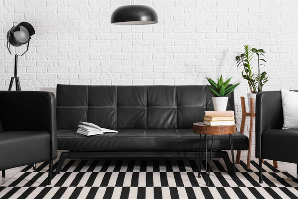 Черный кожаный диван, журнальный столик, кресло и лампы в гостиной