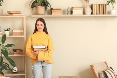 Oturma odasında yığınla kitabı olan genç bir kadın.