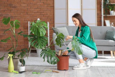 Evdeki çiçekleri sulayan genç kadın.