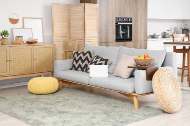 Oturma odasındaki kanepede modern mutfağı ve dizüstü bilgisayarı olan stüdyo dairesi.