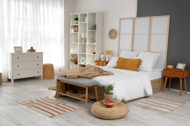 Büyük yataklı, katlanır ekranlı ve pencerenin yanındaki raflı modern yatak odasının içi.