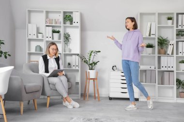 Genç kız ofiste psikologla konuşuyor.