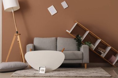 Gri kanepeli dağınık oturma odasının içi ve depremden sonra mobilyaları ters dönmüş.