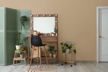 Masası, bitkileri ve katlanmış ekranı olan makyaj odasının içi