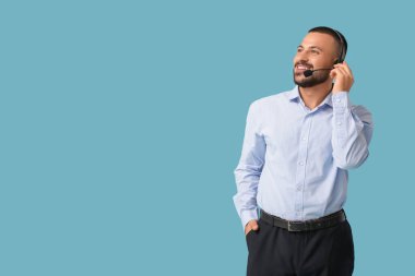 Mavi arka planda kulaklık takan erkek teknik destek ajanı