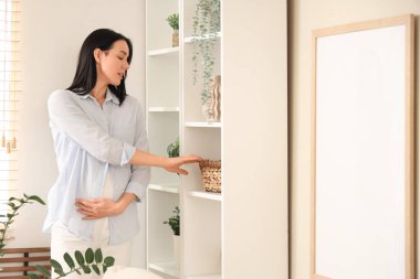 Evde rafta sepeti olan hamile bir kadın.