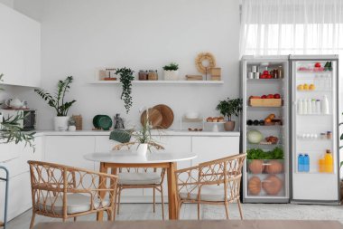 Ev bitkileriyle dolu modern mutfak ve taze yiyeceklerle dolu açık buzdolabı.