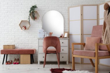 Masanın üzerinde kozmetik ürünleri ve küçük buzdolabı olan modern soyunma odasının şık bir iç mekanı.