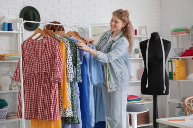 Stüdyoda elbiseleri olan kadın moda tasarımcısı.