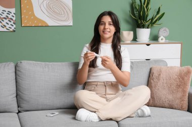 Şeker hastası genç bir kadın evdeki kanepede tükenmez kalem kullanıyor.