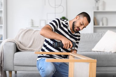 Evinde eğitim masası olan genç bir adam.