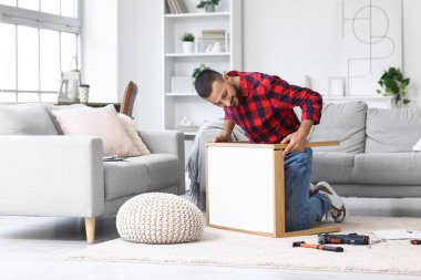 Young man assembling table at home