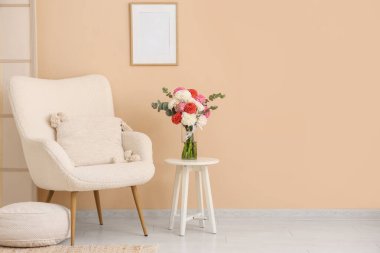 Masada bir buket güzel yıldız çiçeği şık bir koltuk ve duvarda asılı boş bir çerçeve.