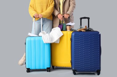 Gri arka planda bavulları, pasaportları ve seyahat aksesuarları olan hoş, genç bir çift. Kış tatili kavramı