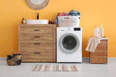 Modern çamaşır makinesi, çekmece sandığı, çamaşır sepetleri ve odada ayna.