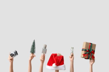 Gri arka planda Noel hediyesi kutusu, mikrofon ve kamera olan gazeteci kadınların elleri