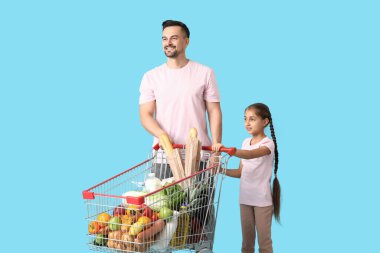 Genç mutlu baba ve kızı mavi arka planda el ele tutuşuyorlar.