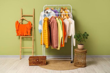 Sonbahar elbiseli raflar ve yeşil duvarın yanındaki merdiven.