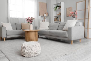 Sıcak kanepeler ve vazodaki manolya çiçekleri odadaki sehpanın üzerinde.