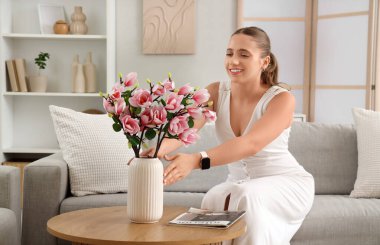 Genç bir kadın ve bir buket manolya çiçeği oturma odasında