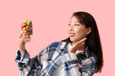 Pembe arka planda renkli fal kurabiyeleri olan genç Asyalı kadın.