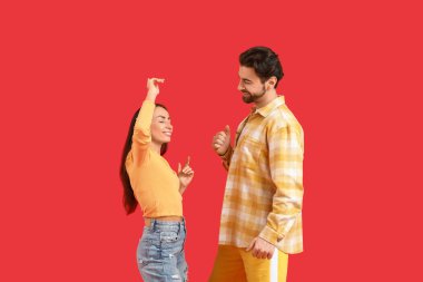 Kırmızı arka planda dans eden mutlu çift.