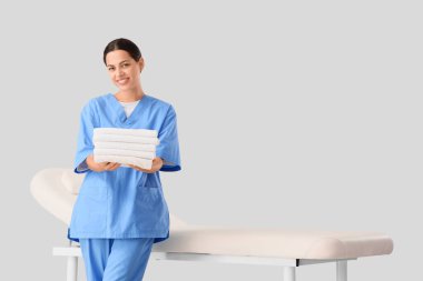 Temiz havlular ve arka planda kanepesi olan kadın masaj terapisti.