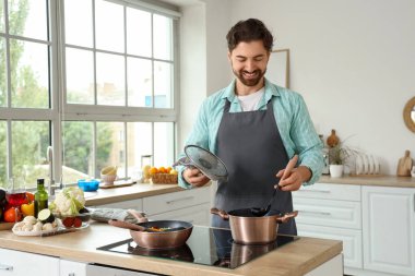 Yakışıklı sakallı adam mutfakta fırında çorba pişiriyor.