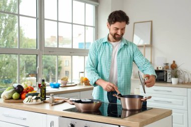 Mutfakta fırında yemek pişiren yakışıklı sakallı adam.