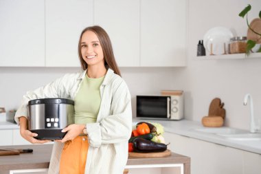 Mutfakta çoklu fırını olan genç bir kadın.