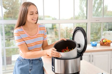 Mutfaktaki çoklu fırından yemek hazırlayan genç bir kadın.