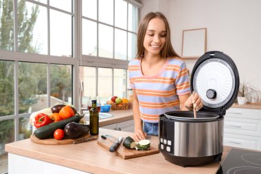 Mutfakta yemek hazırlayan çoklu fırınlı genç bir kadın.