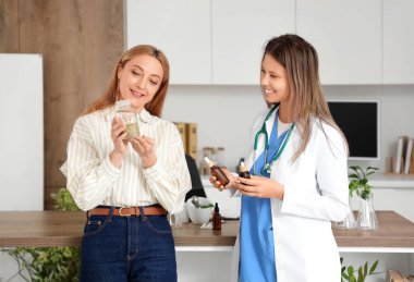 Olgun kadın ve homeopatik doktor. Ofisinde doğal bir ilaç var.