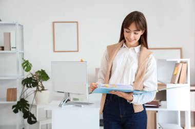 Ofisinde dosyası olan genç bir iş kadını.