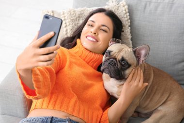 Fransız bulldoglu güzel bir kadın evdeki kanepede selfie çekiyor.