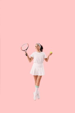 Pembe arka planda raketle zıplayan genç bayan tenisçi