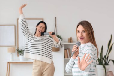 Evde mikrofonlu güzel genç kadınlar karaoke yapıyor.