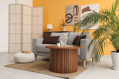 Gri kanepe, ahşap masa ve modern oturma odasının içinde katlanan ekran.