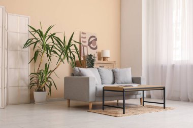 Modern oturma odasının içinde ahşap masalı gri kanepe.