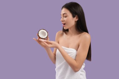 Mor arka planda hindistan cevizi ve kremayla şok olmuş güzel genç bir kadın.