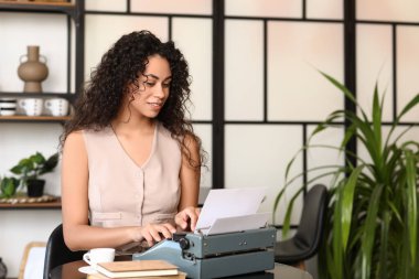 Kafedeki masada daktilo kullanan genç bir Afro-Amerikalı yazar