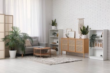 Oturma odasının içinde kanepe, katlanan ekran ve pencerenin yanındaki masa.