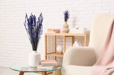 Güzel lavanta çiçekleri, kitaplar ve hafif tuğla duvarın yanında rahat bir koltuk.