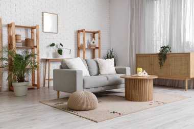 Gri kanepe, çekmece ve raf üniteleriyle oturma odasının içinde.