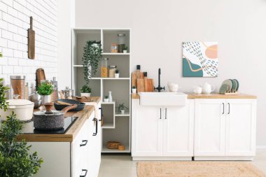 Mutfak tezgahları mutfak içinde mutfak gereçleri ve raf üniteleriyle dolu.