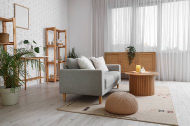 Gri kanepe, pencere ve raf üniteleriyle oturma odasının içinde.