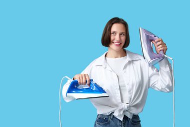 Mavi arka planda demirleri olan genç bir kadın.